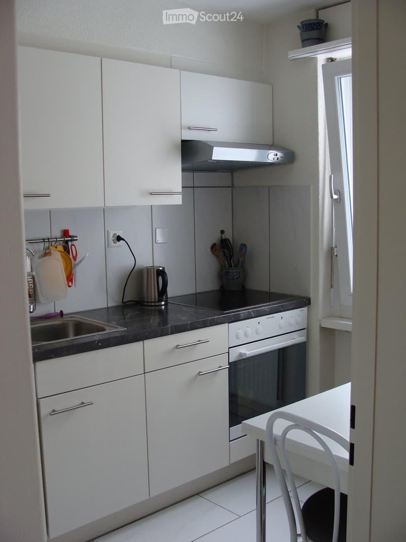 white kitchen with marble counter top, sink, electric kettle, stove, and oven, white cabinets, white table, chairs