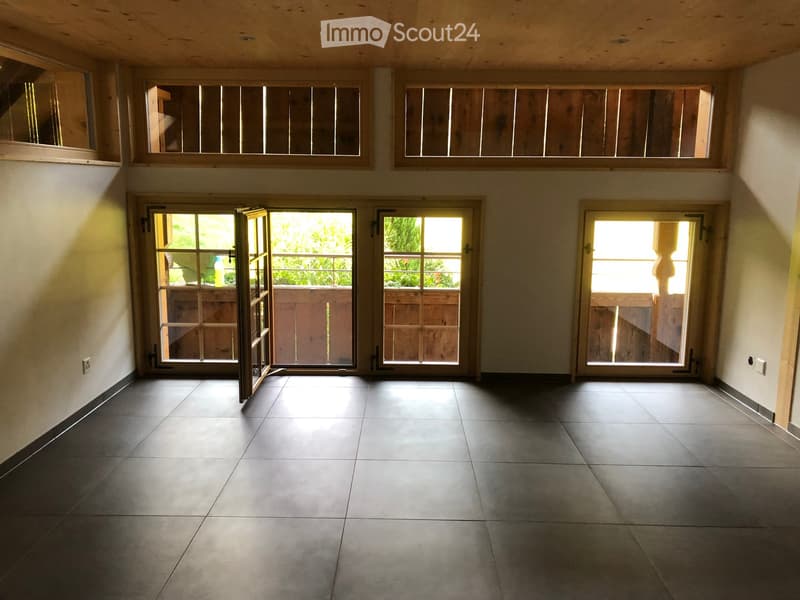 Empty room with tiled floor, multiple doors and windows, and natural light coming in.