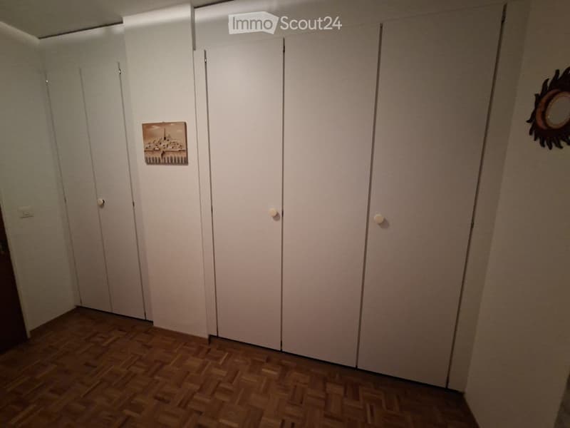 Empty room with wooden flooring, white closet doors, and two small wall decorations.
