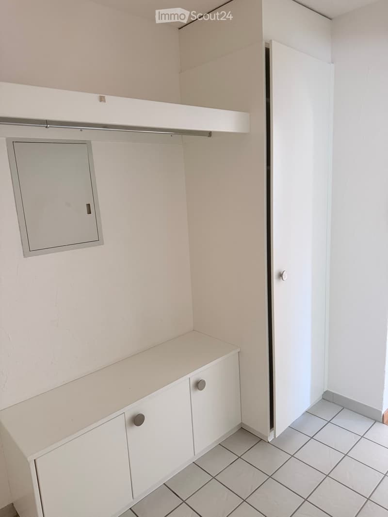 Empty room with white tiled floor, white walls, and built-in white cabinets with silver handles.
