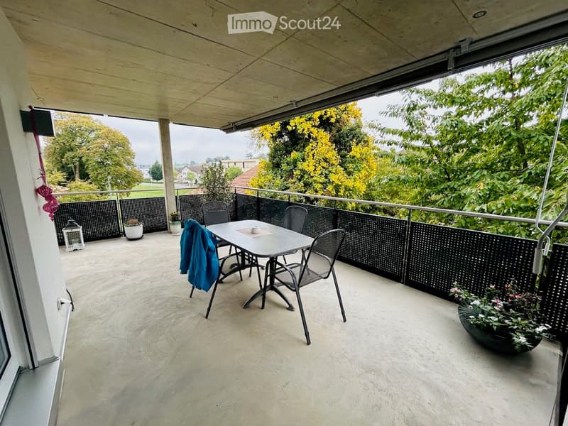 Balcony with a table and chairs, surrounded by greenery and a view of the landscape.