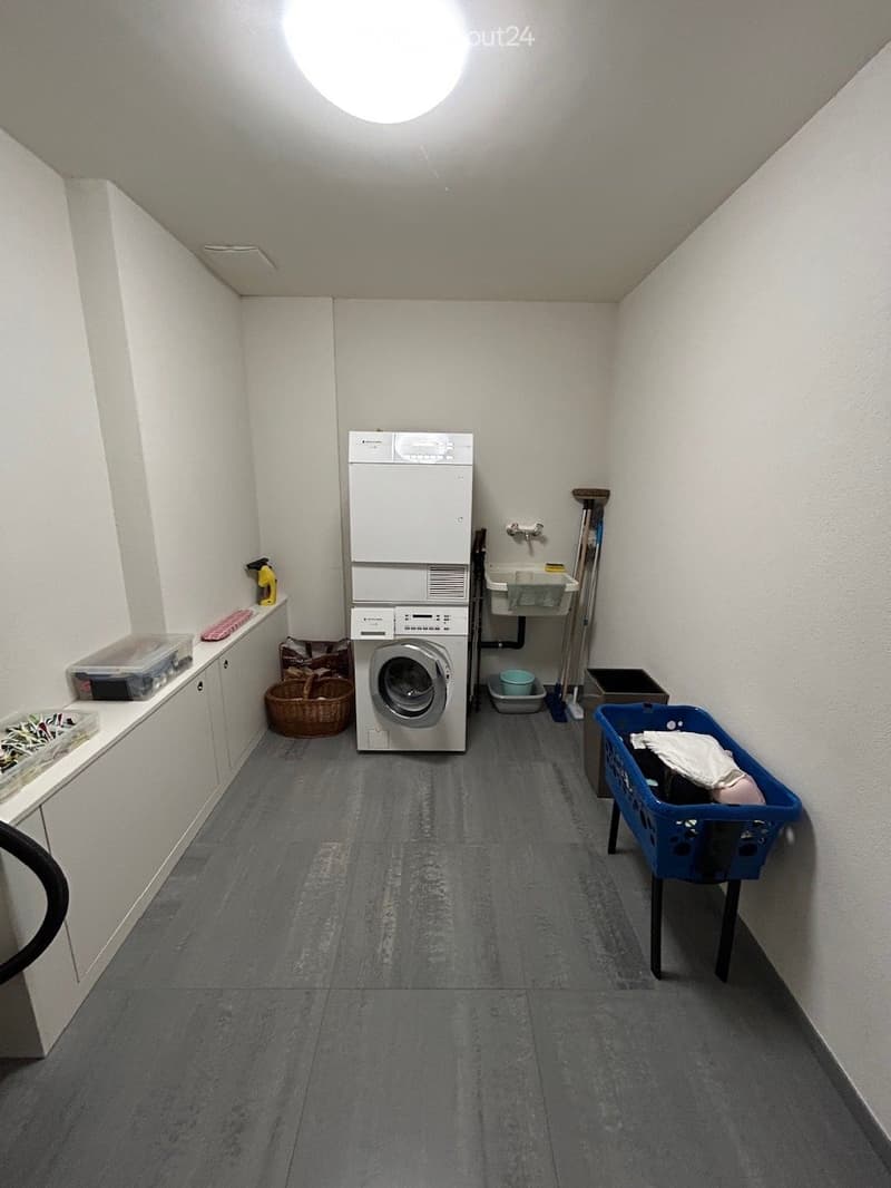 Laundry room with a washing machine, sink, cabinet, and baskets.