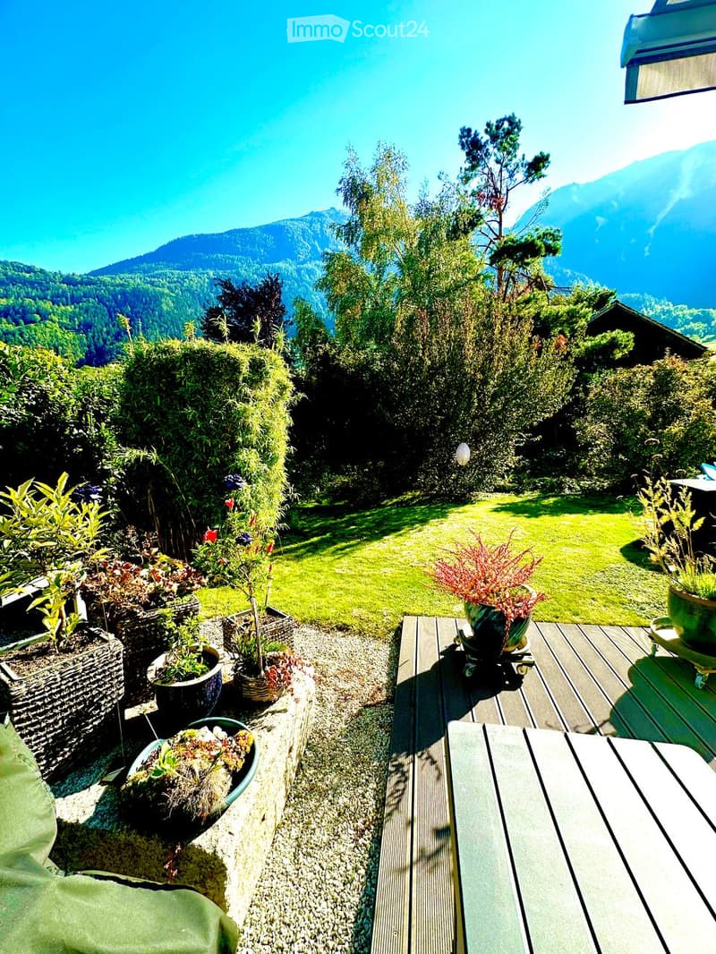 Garden with wooden deck, potted plants, and scenic mountain view.