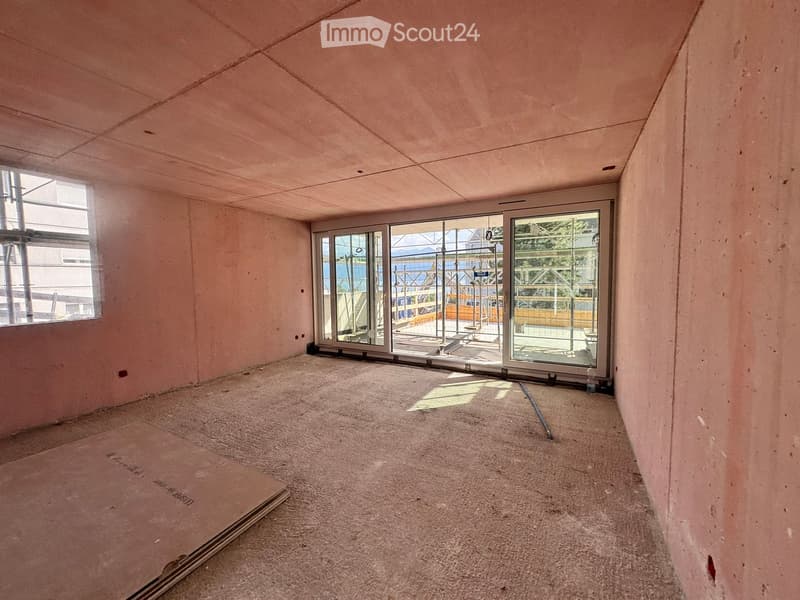 Empty room with unfinished walls and carpeted floor, large glass sliding doors leading to an outdoor area.
