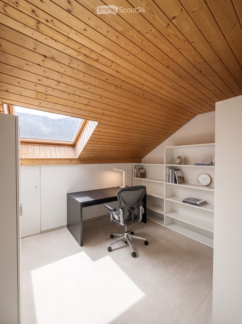 Modern, minimalist office space with a sleek black desk, ergonomic chair, white bookshelf, and a skylight providing natural light.