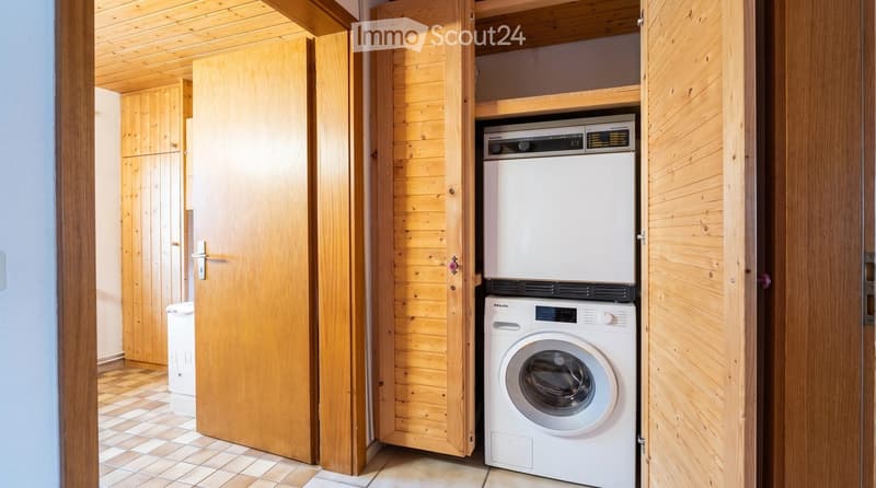 Bathroom with wooden walls and ceiling, featuring a white washing machine and a white dishwasher stacked vertically.