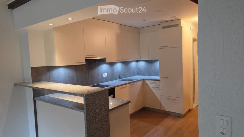 Modern kitchen with light-colored cabinets, granite countertop, and stainless steel sink.