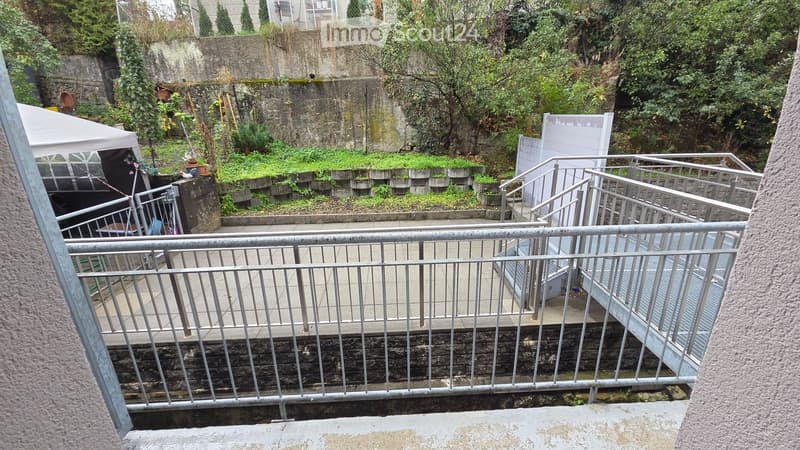Raised garden area with metal railings, small staircase, and greenery.