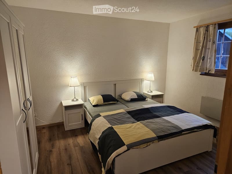 Cozy bedroom with a double bed, nightstands, lamps, and a window with curtains.