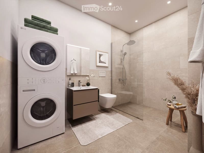 Modern bathroom with a washing machine, sink, toilet, shower, and decorative elements like a framed picture and a small plant.