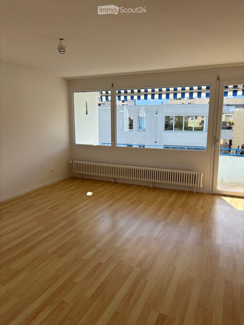 empty room, hardwood floors, large windows, sliding glass doors, white radiator, electrical outlet