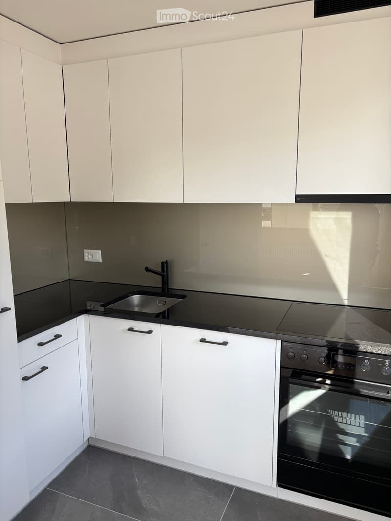 white cabinets, black countertops, stainless steel sink, glass splashback, black stove, black oven