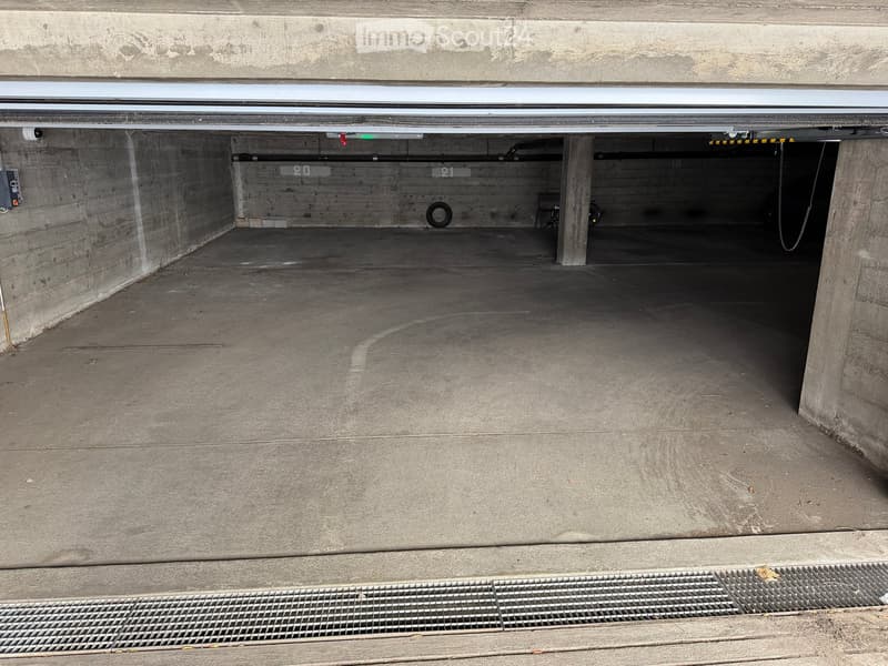 Underground parking garage with concrete walls, numbered parking spaces, and a few parked vehicles visible in the background.