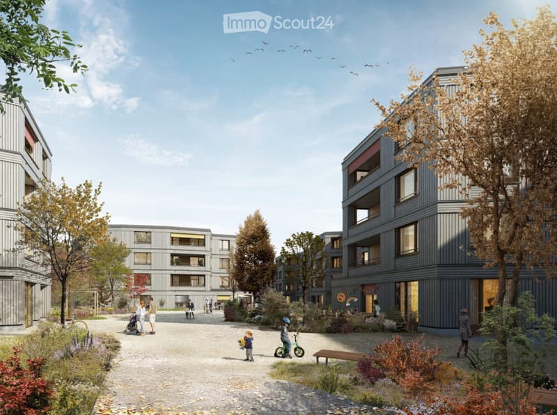 Modern residential complex with multiple apartment buildings, surrounded by greenery, pathways, and outdoor seating areas. People are seen walking and interacting in the courtyard.