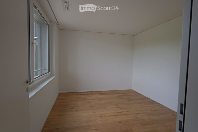 Empty room with wooden flooring, white walls, and a single window with a white sill. No furniture or equipment is present.