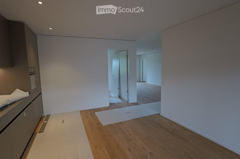 Empty room with light-colored walls, wooden flooring, and a doorway leading to another room. No furniture or equipment is present.