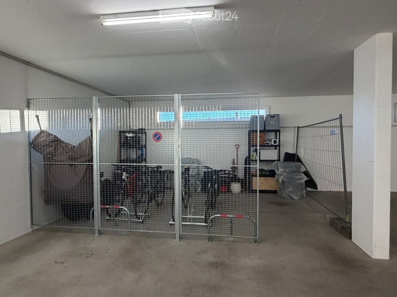 {"type": "Garage", "objects": [], "description": "Empty garage with concrete floor, white walls, fluorescent lighting, and a fenced-off area containing bicycles and storage items.", "localized_descriptions": {"EN": "Empty garage with concrete floor, white