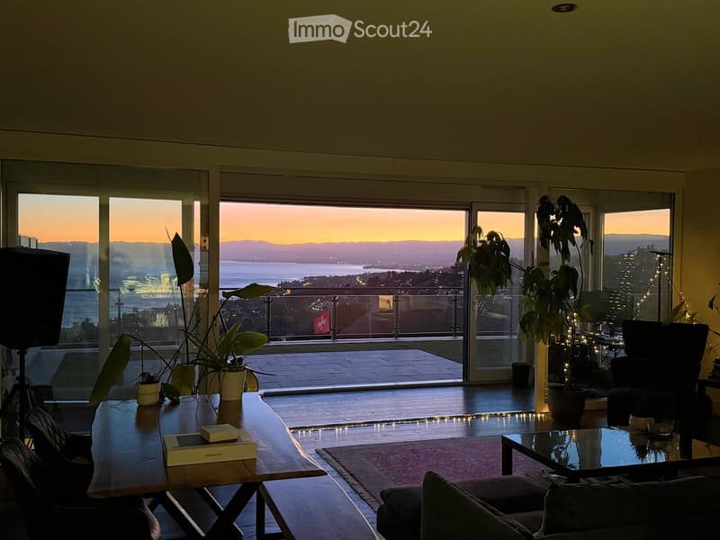 Modern living room with large windows offering a scenic view, featuring a sofa, coffee table, side table, and potted plants.