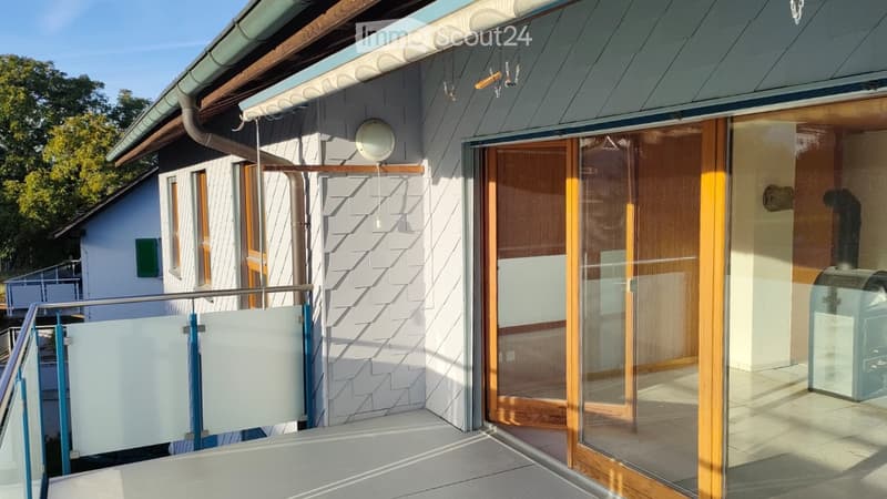 Balcony with glass sliding doors, metal railing, and a view of the house exterior.