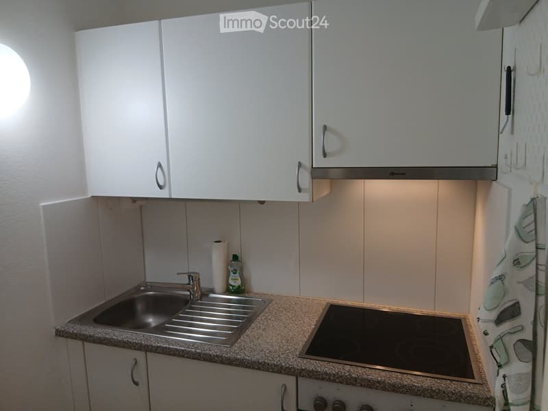 Modern kitchen with white cabinets, granite countertop, stainless steel sink, electric stove, and a paper towel roll on the counter.