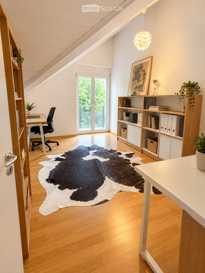 Bright, airy room with wooden flooring, a large cowhide rug, a desk with a chair, a bookshelf, and a potted plant. Large windows and a door lead to a balcony.
