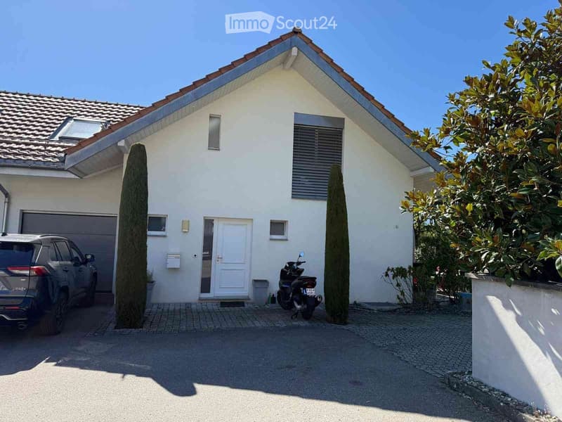 Single-story house with white exterior, garage, and driveway. Features include a front door, windows, and a scooter parked outside.