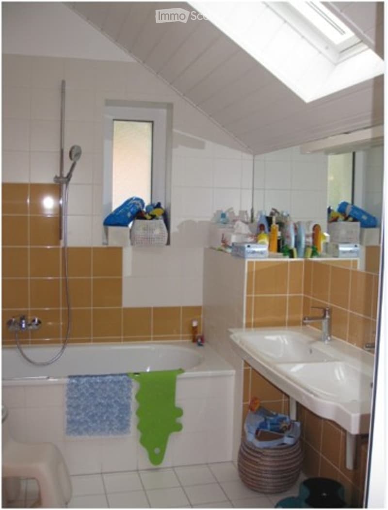 Bathroom with a bathtub, shower, sink, and mirror. The walls are tiled in orange and white, and there are towels and storage baskets visible.