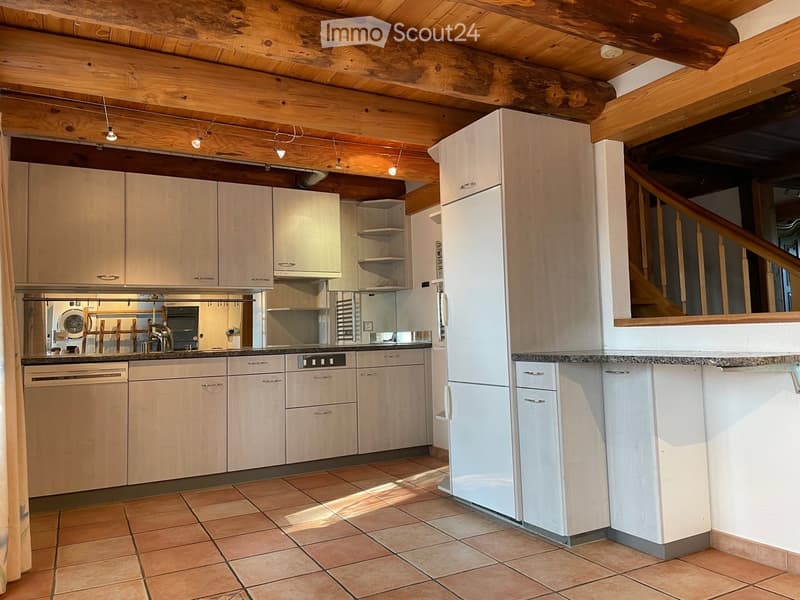 Modern kitchen with light wood cabinets, stainless steel appliances, and a tiled floor. Features a refrigerator, dishwasher, oven, and sink.