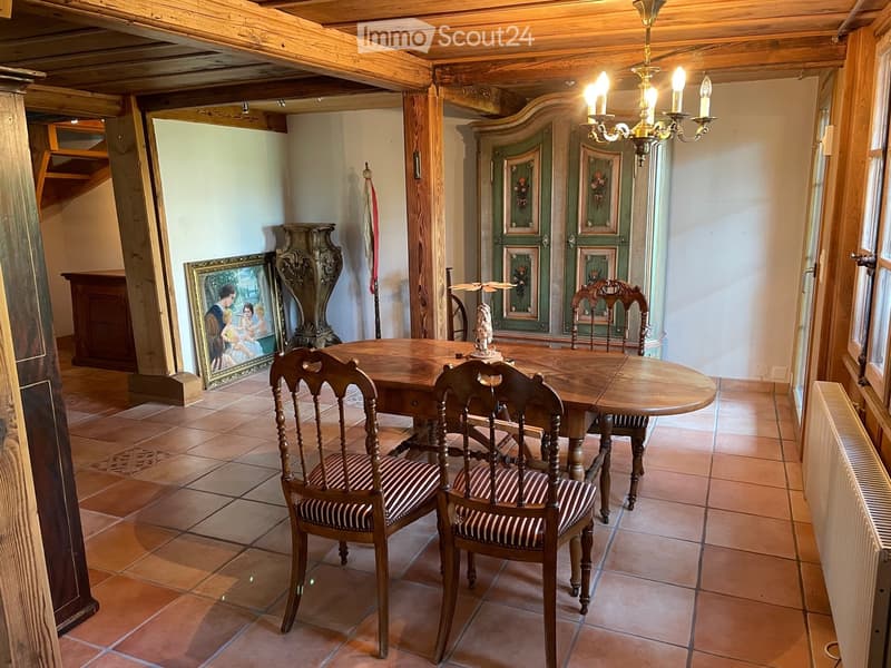 Dining room with wooden dining table, chairs, cabinet, picture frame, chandelier, and radiator.