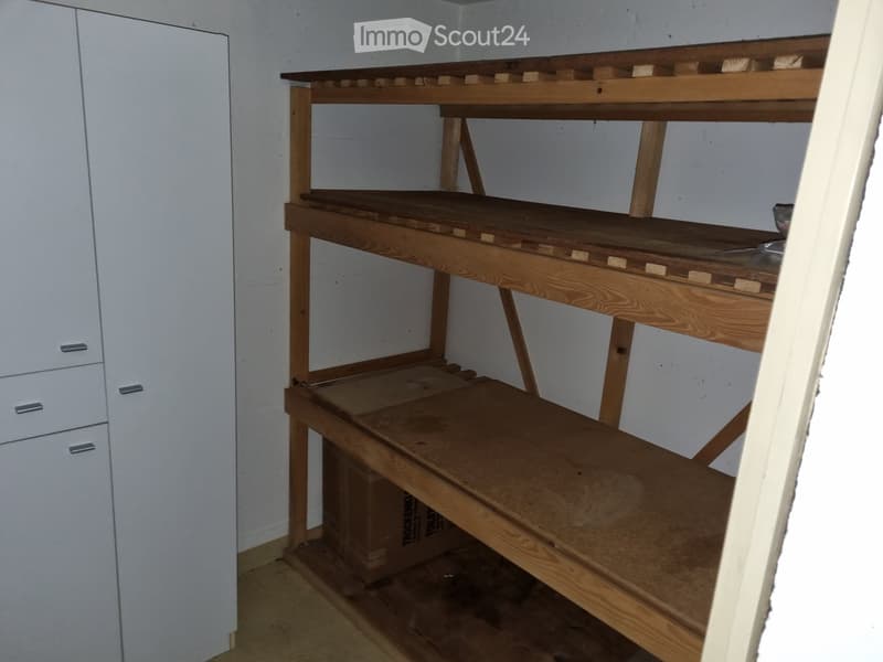 Empty room with wooden shelving unit and white cabinet. No furniture or personal items present.