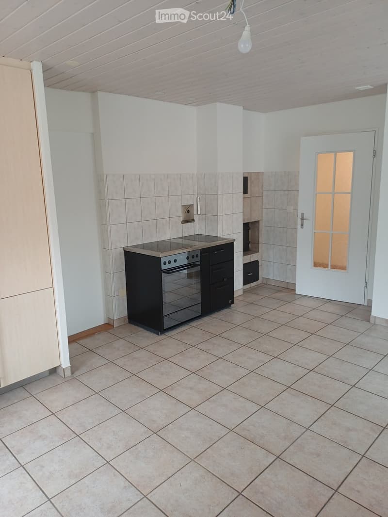 Modern kitchen with tiled walls, tiled floor, built-in oven, and white cabinets.