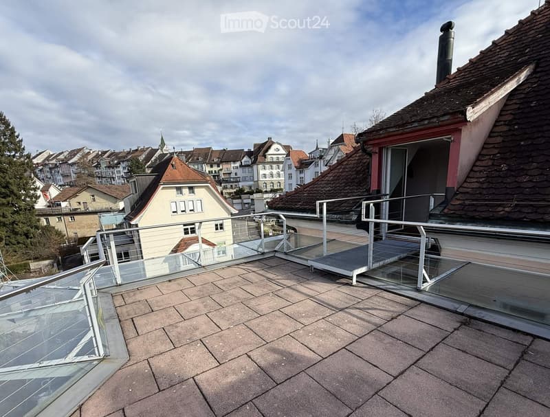 Roof balcony, brick tiles, view of city, glass fence, sloped roof, metal handrail