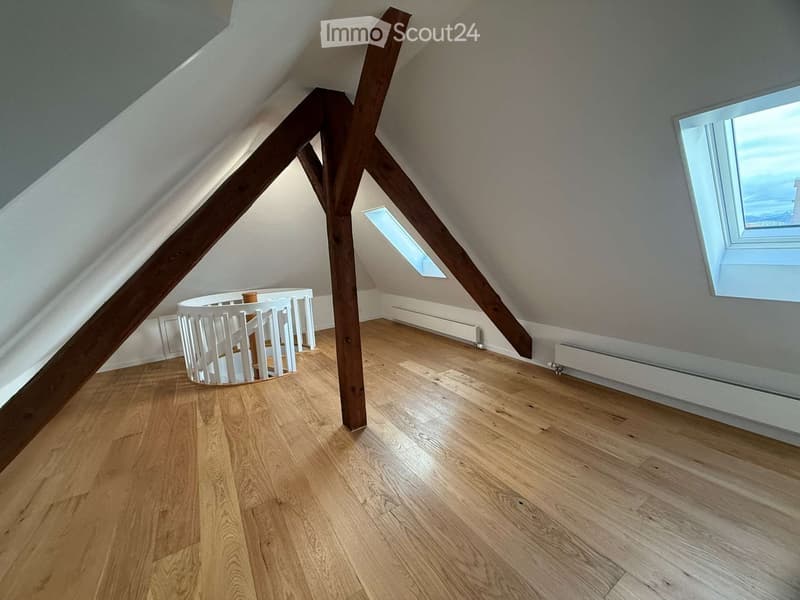 Wooden attic room with wooden beams, spiral staircase, radiators, two skylights, wooden floor