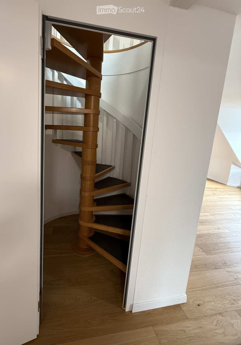 Spiral staircase with wooden steps, a hallway, and a white door