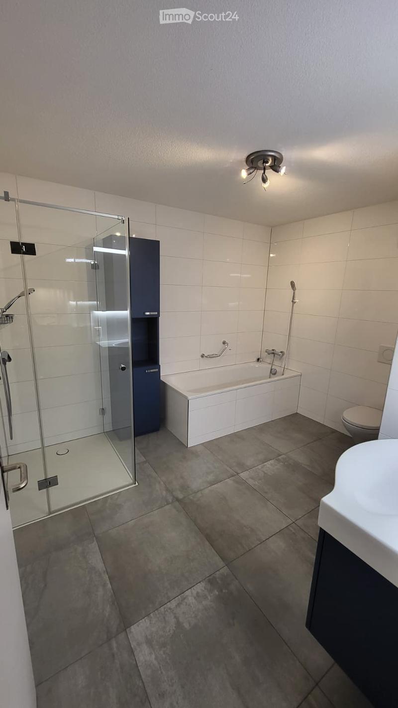 Glass shower, white bathtub, white sink, modern blue and white cabinet, white tiles, white ceiling