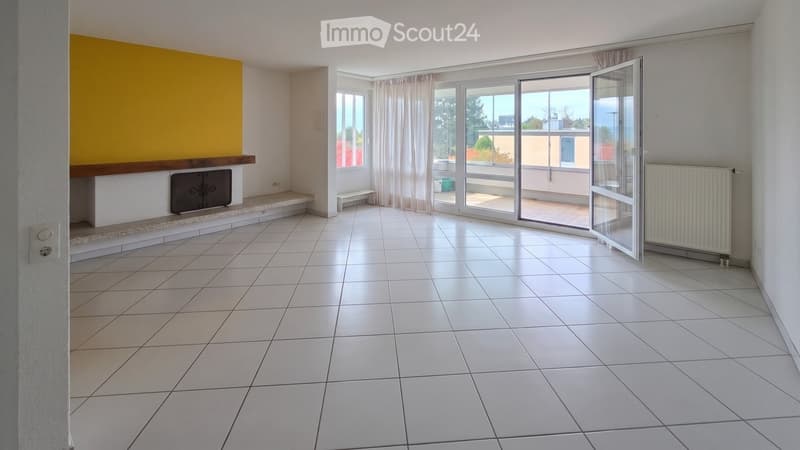 Empty living room with white tiled flooring, large windows with curtains, a fireplace, and a sliding glass door leading to a balcony.