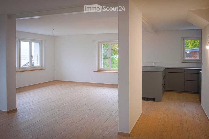 Empty room with wooden flooring, white walls, and large windows. No furniture or equipment present.