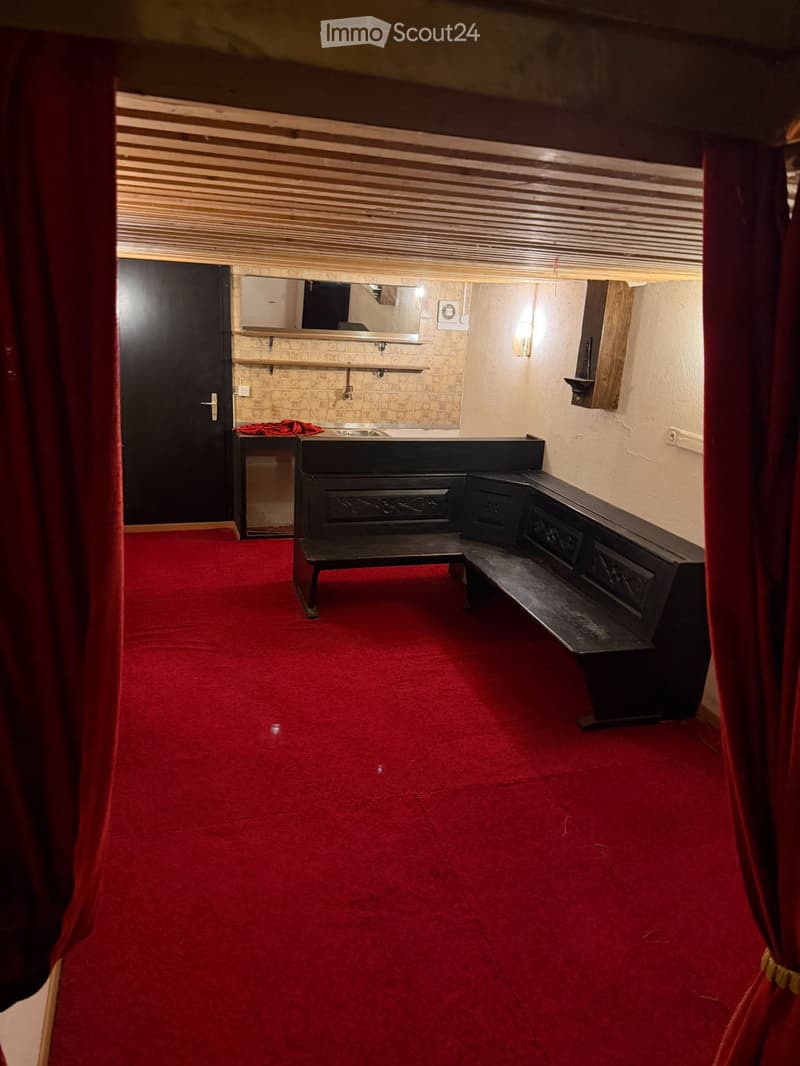 Small room with red carpet, wooden bench seating, sink, mirror, and shelves.