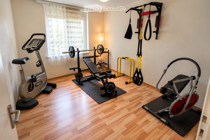 Well-equipped home gym with wooden flooring, large window with curtains, exercise bike, weight bench, barbell, cable machine, and treadmill.