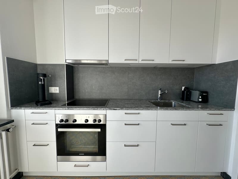 Modern kitchen with white cabinets, stainless steel appliances, granite countertop, and built-in oven.