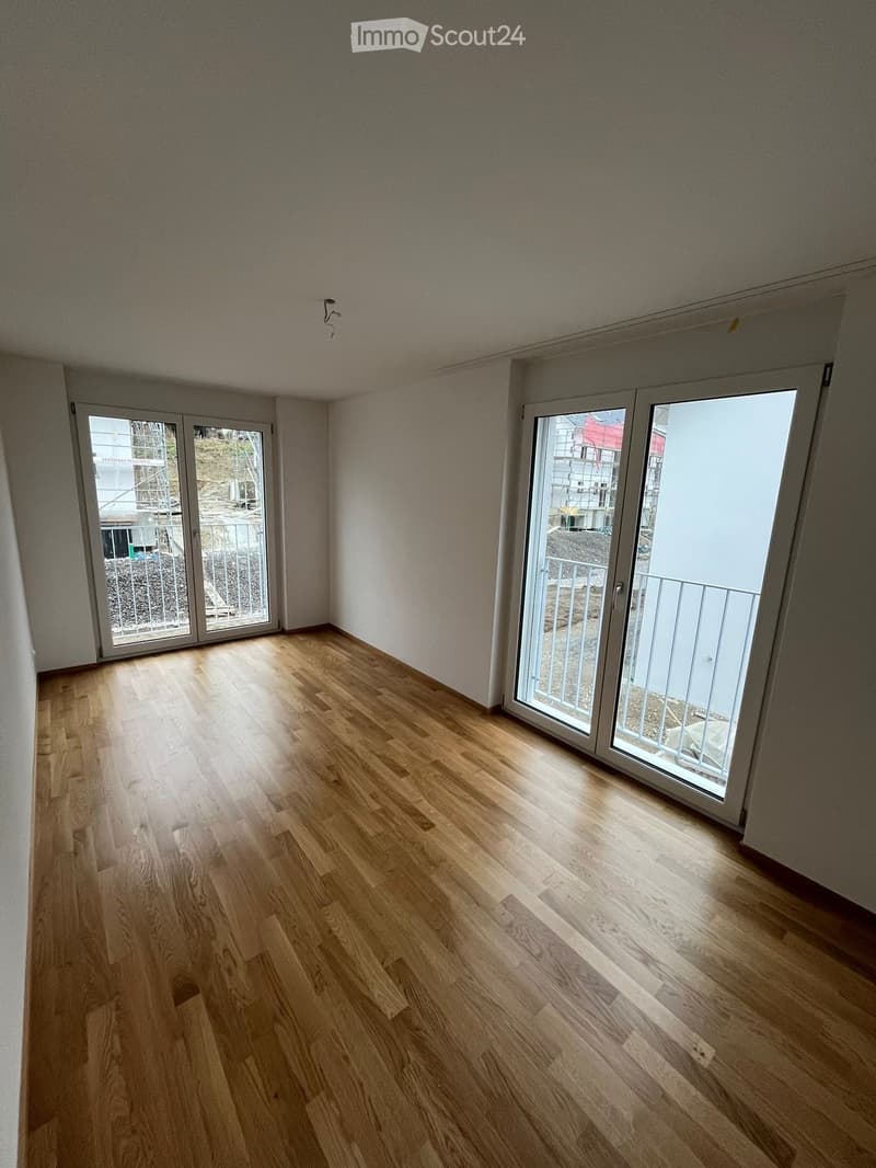 Empty room with wooden flooring and large sliding glass doors leading to a balcony.