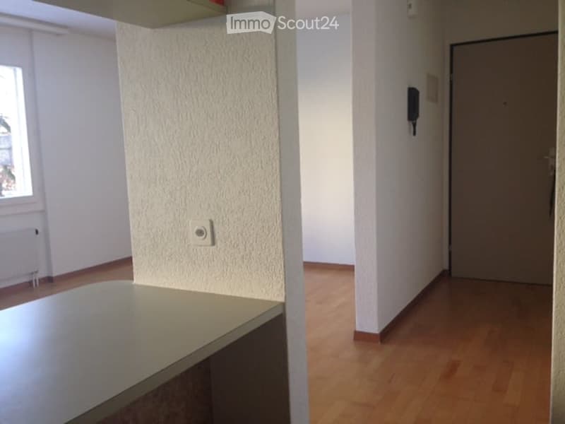 Empty room with wooden flooring, white walls, and a small table. No furniture or equipment present.