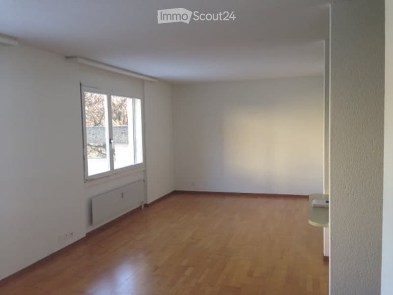 Empty room with wooden flooring, white walls, and a window with a view of the outside. No furniture or equipment is present.