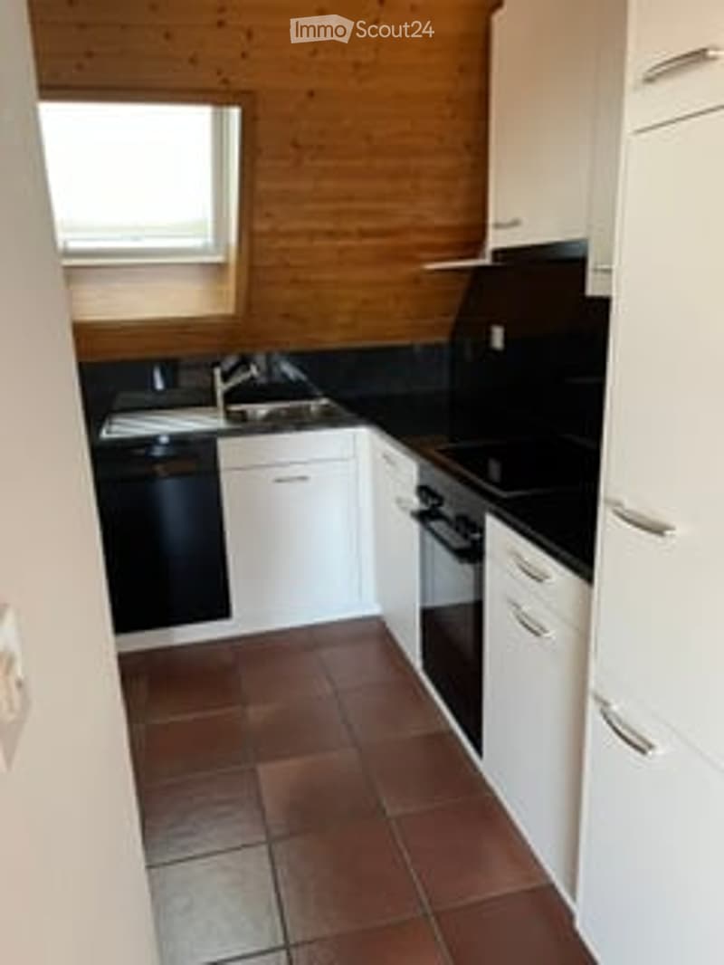 Modern kitchen with white cabinets, black countertops, and a tiled floor. Features include a sink, faucet, dishwasher, and oven.