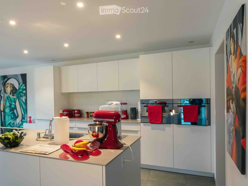 Modern kitchen with white cabinets, a red stand mixer, and various appliances on the counter.