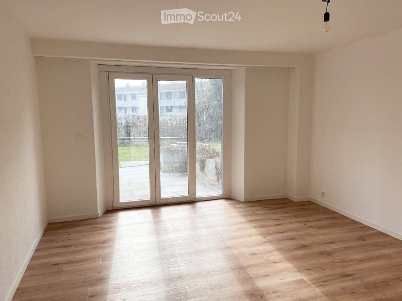 Empty room with wooden flooring and large glass sliding doors leading to an outdoor area.
