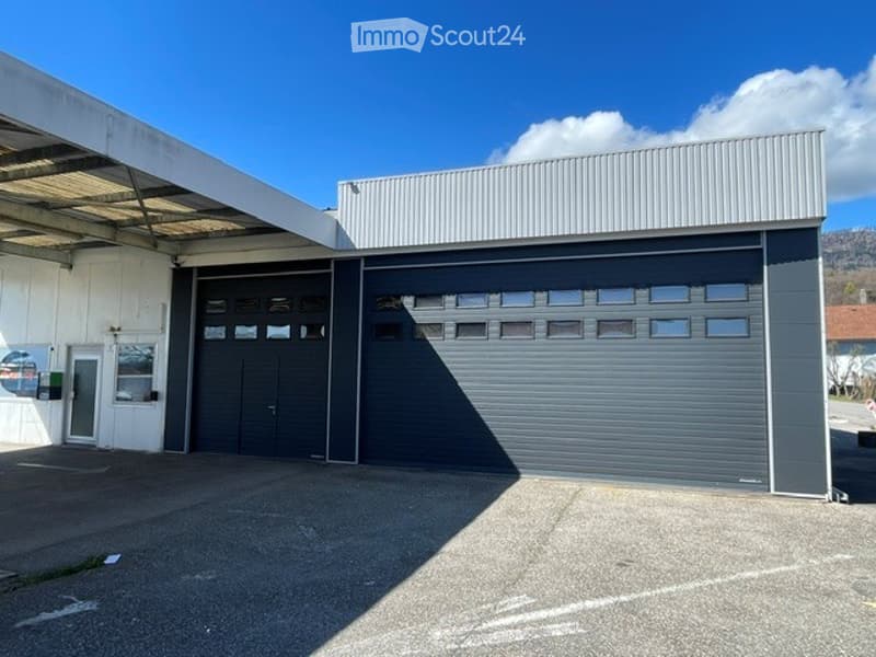 Industrial-style building with large garage doors and a covered entrance area.