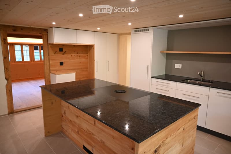 Modern kitchen with a central island, black granite countertop, white cabinets, and a sink with a modern faucet.