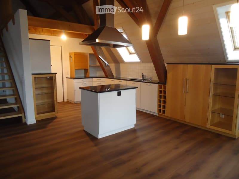 Modern kitchen with wooden floors, white cabinets, central island, and stainless steel appliances.