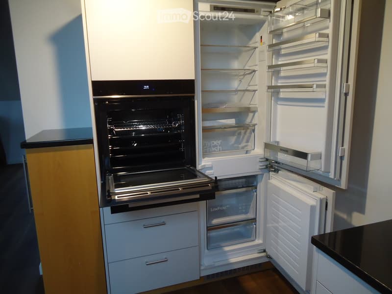 Modern kitchen with white cabinets, a stainless steel refrigerator, and a built-in oven. The refrigerator and oven doors are open, revealing their interiors.